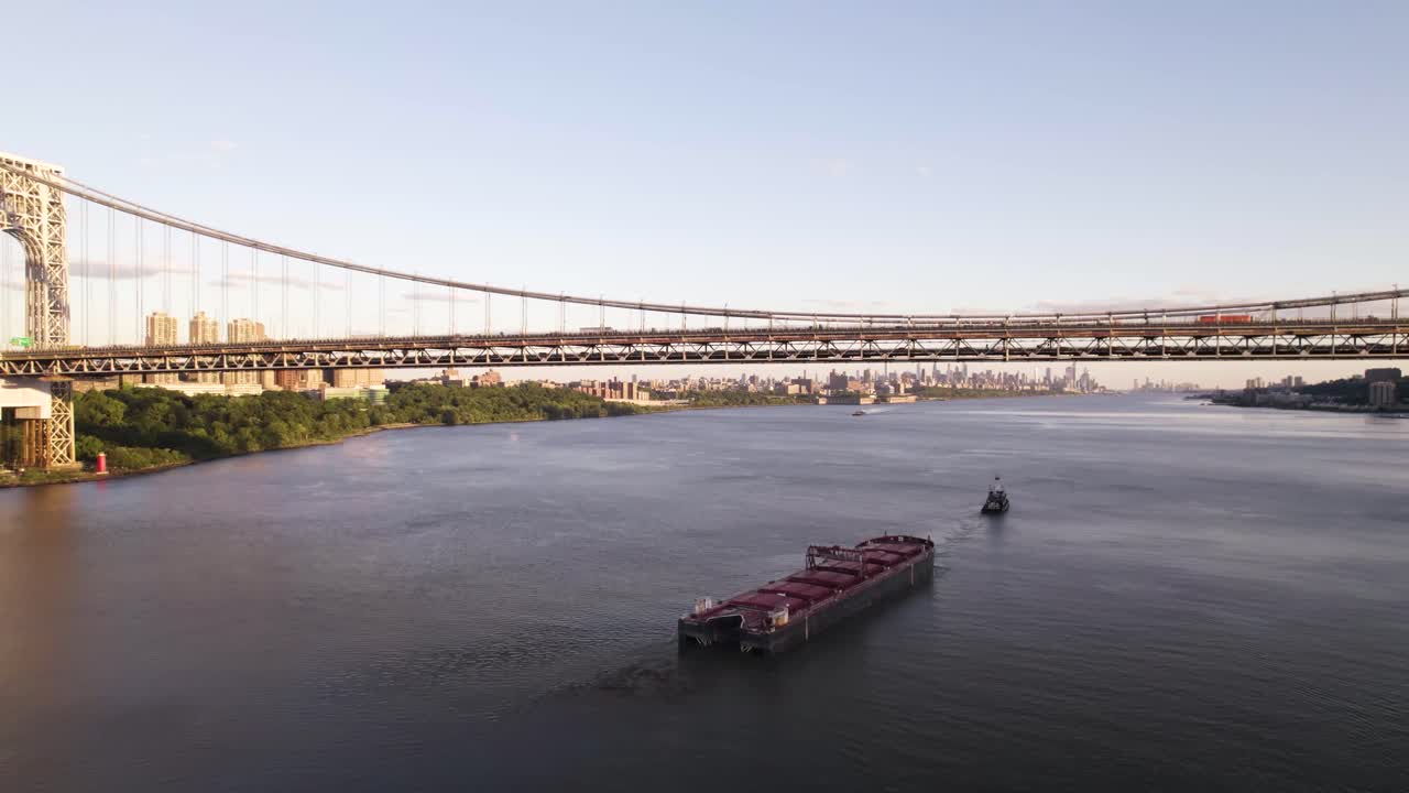 Long aerial pan out of commercial ship entering New York City under George Washington Bridge
