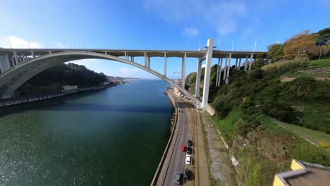 fpv drone over rooftops under main structure of arrabida bridge porto portugal