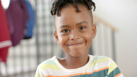 niño afroamericano con una sonrisa alegre, con una camisa a rayas en casa