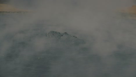 Steaming-and-bubbling-mud-pool-in-Hverir-geothermal-area,-telephoto-slowmo