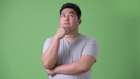 young handsome overweight asian man against green background