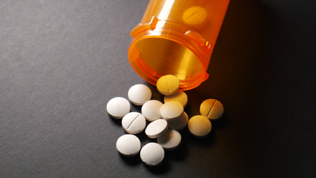 White  medical pills spilling on black background