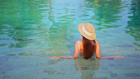 unrecognizable fit girl lying in shallow swimming pool water in vietnam, copy space