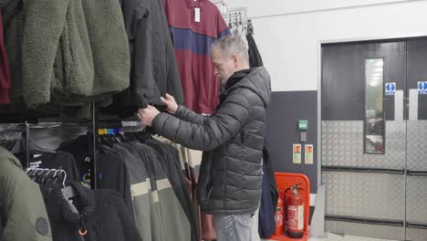 hombre maduro de cabello gris mirando en la tienda por ropa nueva