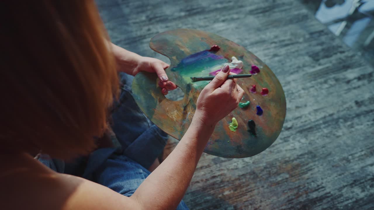 Artista che mescola i colori su una tavolozza con un pennello