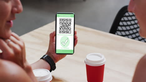 hombre en un café mostrando un teléfono inteligente con certificado de vacunación contra la covid y código qr en la pantalla