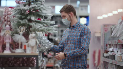 a man in a protective mask in a jewelry store and garlands with toys for christmas trees and at home. christmas garlands and decor