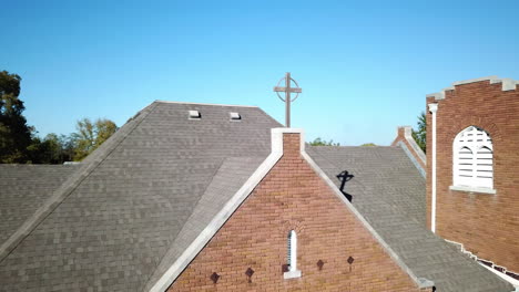 Overhead-drone-shot-of-brick-building-surrounded-by-trees-under-clear-sky