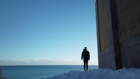 wide shot of a man raising hands in salutation on a hillside overlooking lake ontario