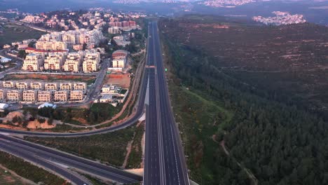 aerial view of an empty highway, residential buildings, and forest landscape at dawn