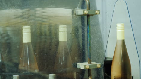 bottles of wine moving along the conveyor to the car where they are washed with water