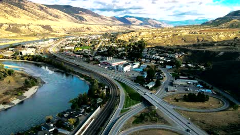 hyper-lapse dolly in drone shot of bridges and the highway 1 and yellowhead highway in kamloops bc canada with train trucks, the thompson river on a cloudy day in a desert environment