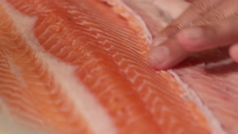 ein koch schneidet das fleisch eines frischen lachsfilets mit einem scharfen messer für sushi zu