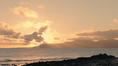 sunset over the ocean with islands in the background