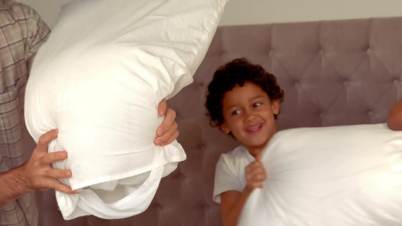 미소 짓는 히스패닉 가족 이 베개 싸움을 하고 있다