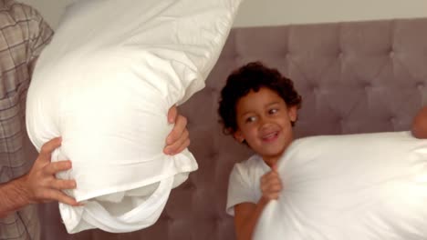 una familia hispana sonriente haciendo una pelea de almohadas
