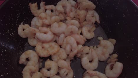 spanish garlic shrimp in black frying pan wok, close up pedestal down