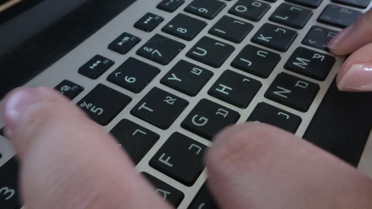 Detailed front view close-up of hands on a laptop keyboard, fingers pressing keys.