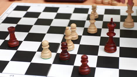 two unrecognizable people are playing chess on a light wooden background. games and activities for people concept