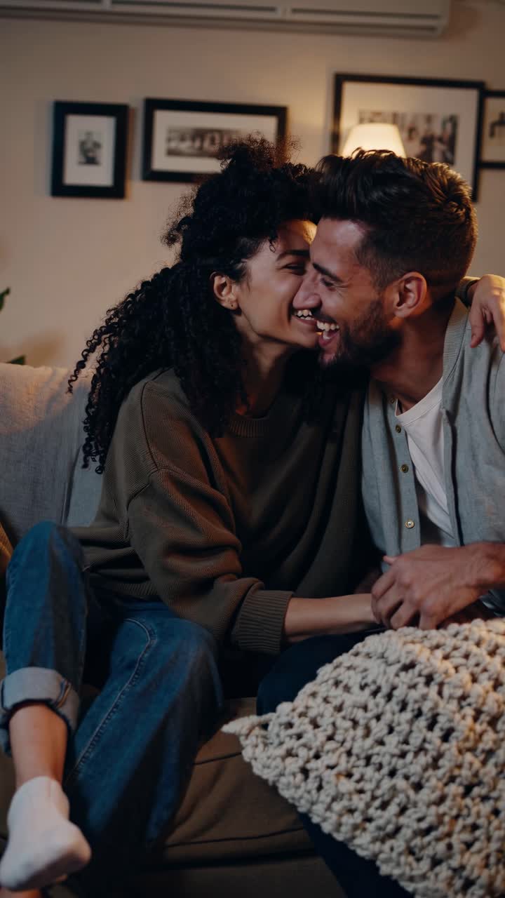 A cozy video scene of a smiling couple on a sofa, captured from a side angle