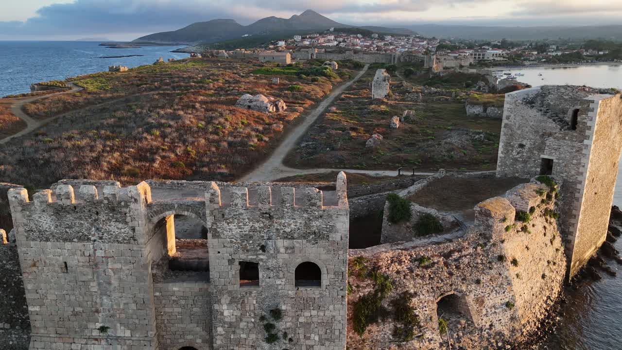 Methoni,Messenia,Peloponnese,Aerial view backwards from Methoni Castle ruins inside towards Bourtzi Tower during golden hour with white clouds and hills at the back ground