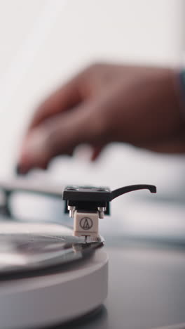 un hombre pone un lápiz de phono en un disco de vinilo en un tocadiscos. un amante de la música masculino llena el día con la alegría de escuchar música en un dispositivo vintage. vinilo de colección de la vieja escuela