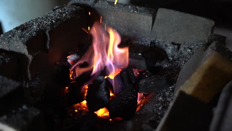 pieza de hoja de metal de cuchillo calentada por herrero en un horno abierto de ladrillo antes de dar forma y martillar en el yunque, toma de primer plano manual