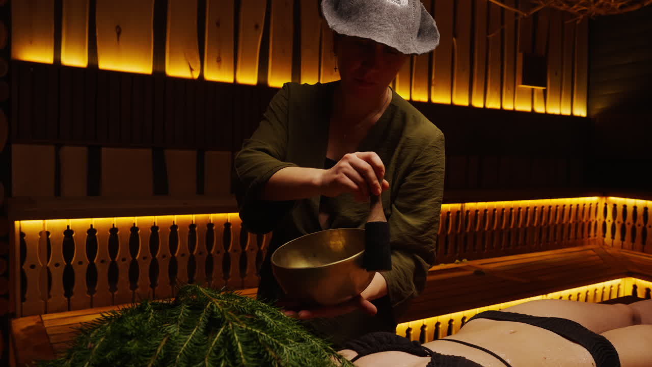 Woman performing sound healing session with singing bowl in a wooden cabin