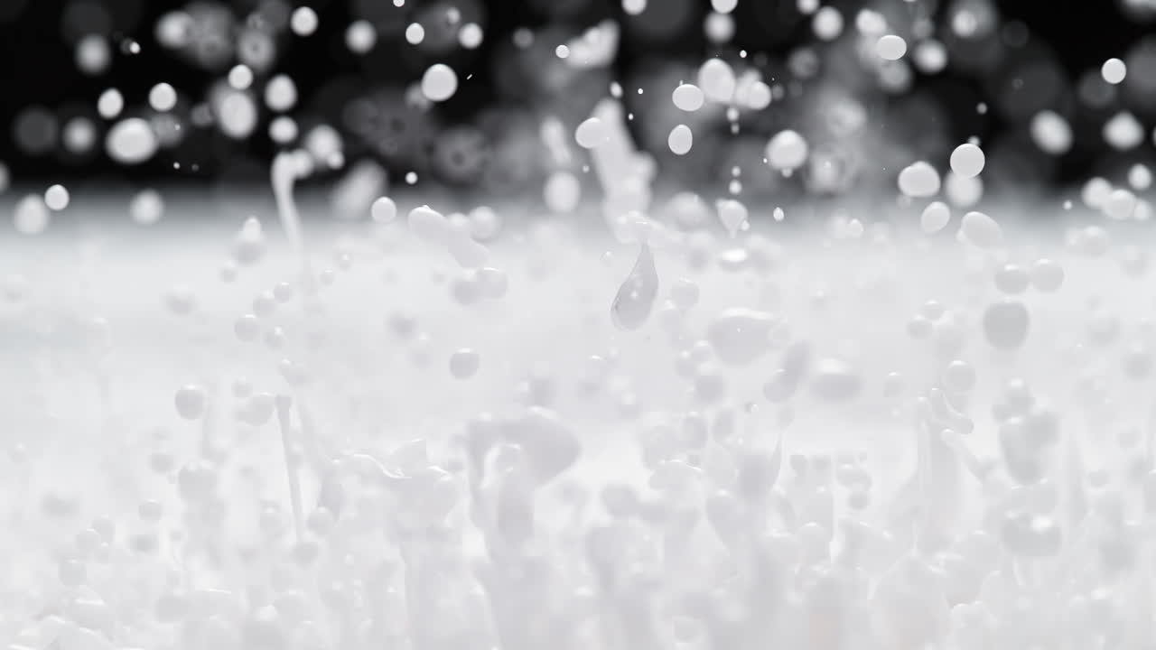 Milk Splashes And Creates White Droplets And Waves On the Black Background In Macro and Slow Motion