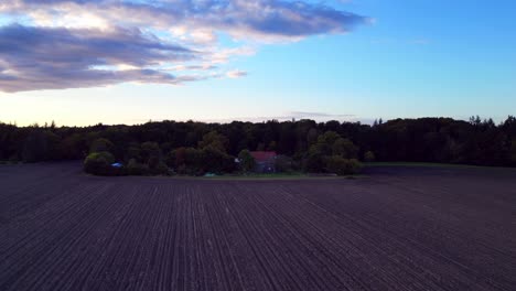the edge of a forest bordering a plowed field in germany. stunning aerial view flight descending drone
