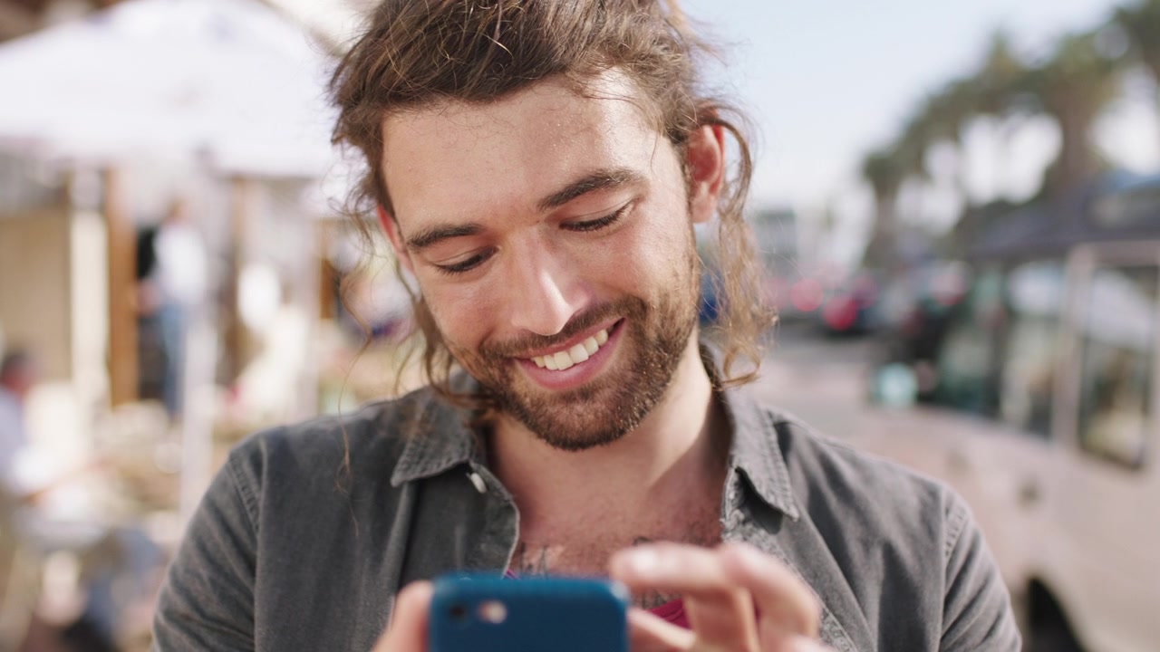 Giovane sorridente mentre usa lo smartphone all'aperto