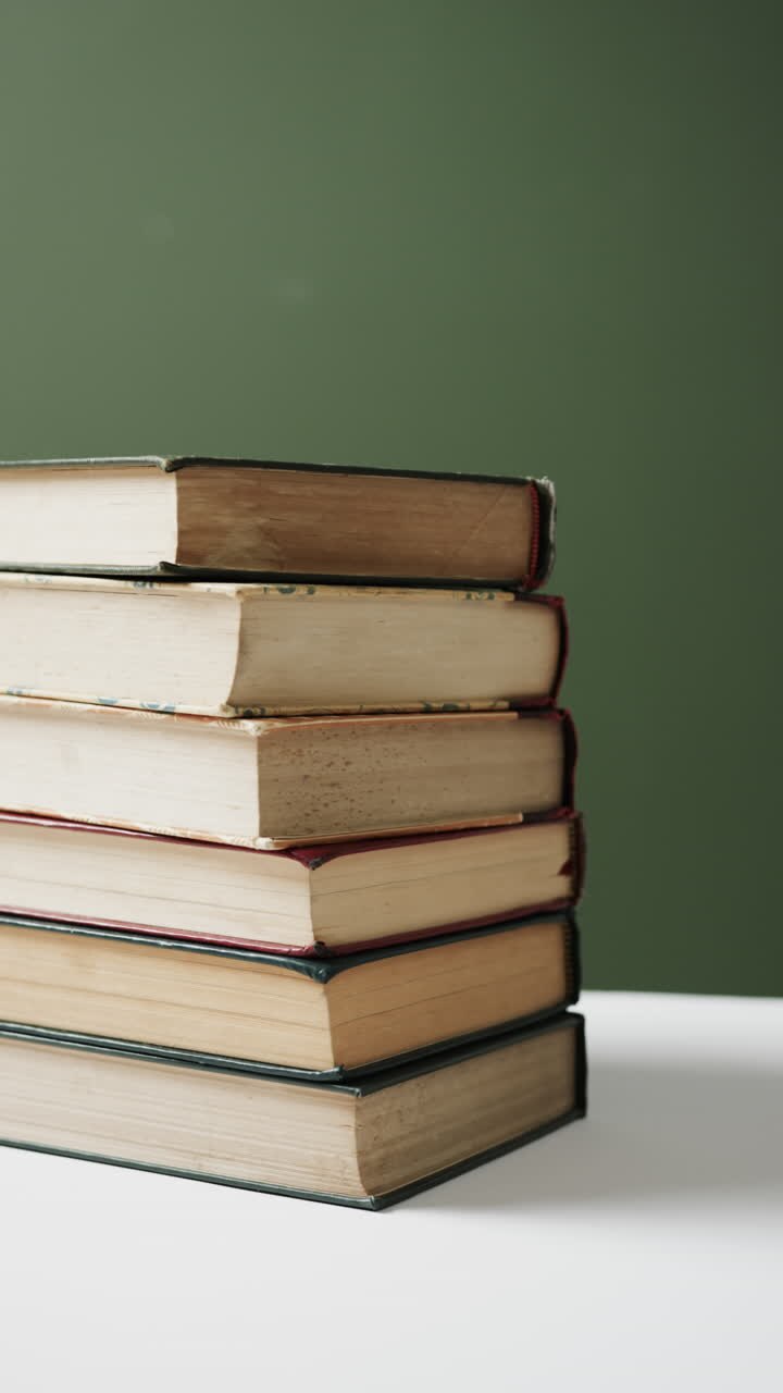 Video vertical de una pila de libros con espacio para texto sobre fondo verde, en cámara lenta