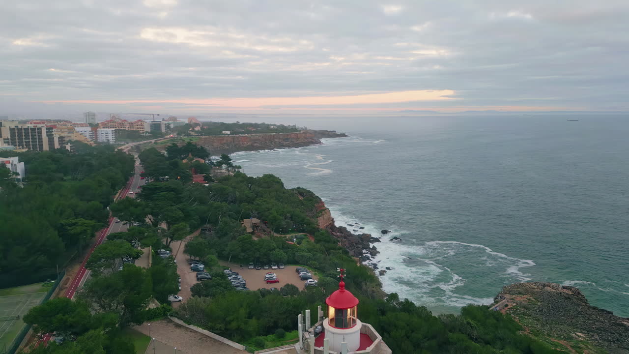 Twilight coastal town washed by  ocean water. Lighthouse on seashore