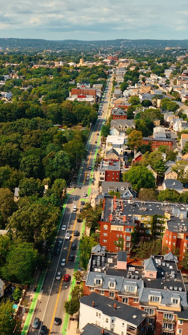 Rising over rooftops of low-rise buildings in Cambridge, Massachusetts, USA. Green city scenery on sunny day from top. Vertical video