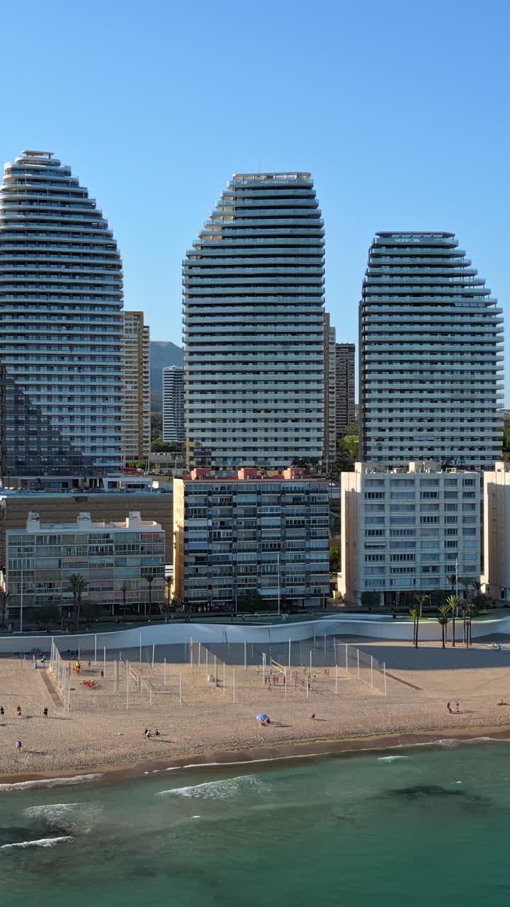 Aerial drone view of the buildings along the coastline and the sea in Benidorm, Spain in daylight. Vertical