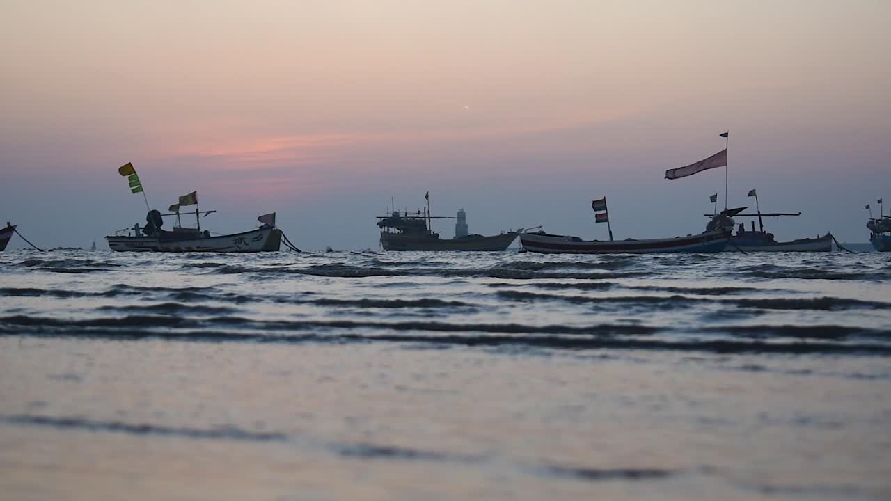 해안 비디오 배경 근처에 정박한 작은 파도와 다채로운 하늘을 가진 어선 실루엣