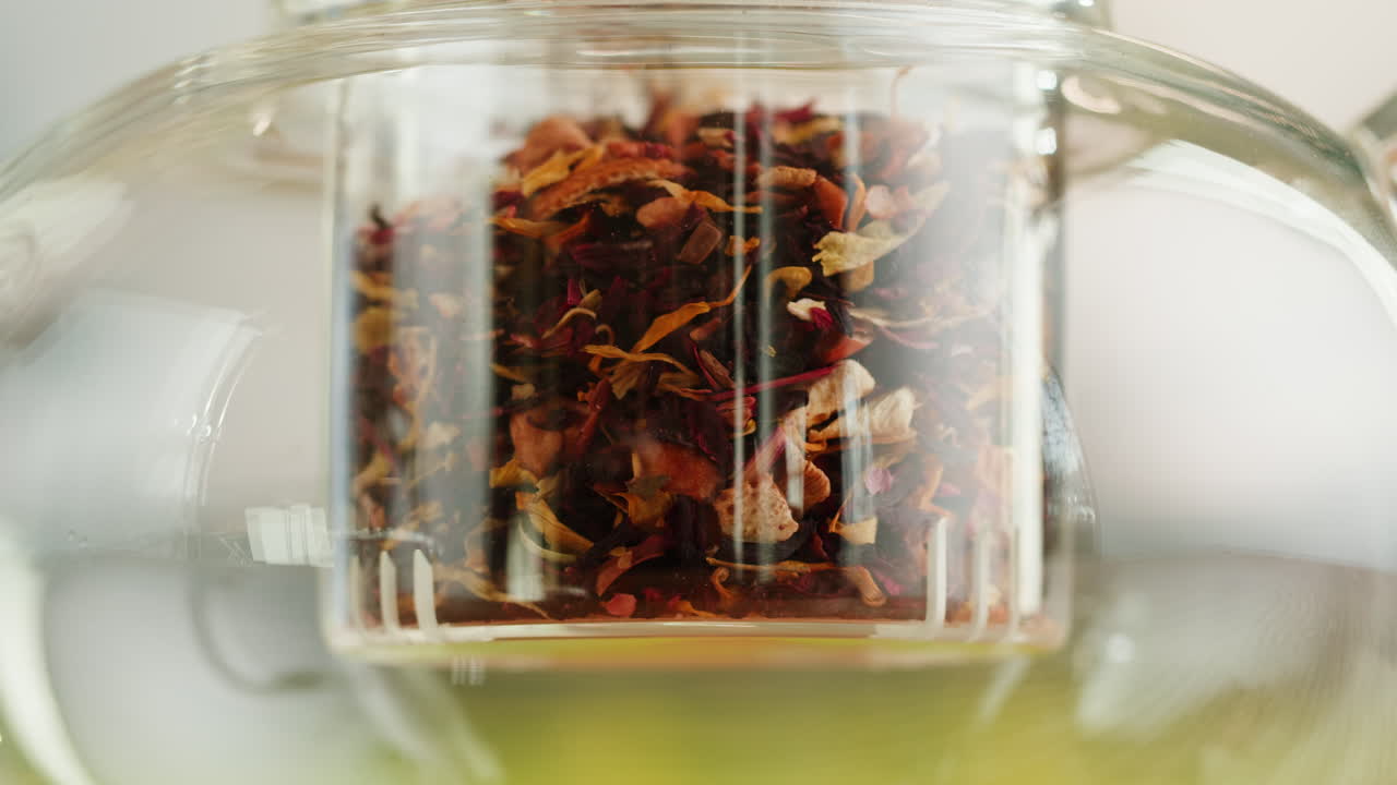 Close-up of Dried Flower Petals and Herbal Tea Brewing in a Glass Teapot
