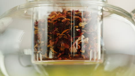 close-up of dried flower petals and herbal tea brewing in a glass teapot