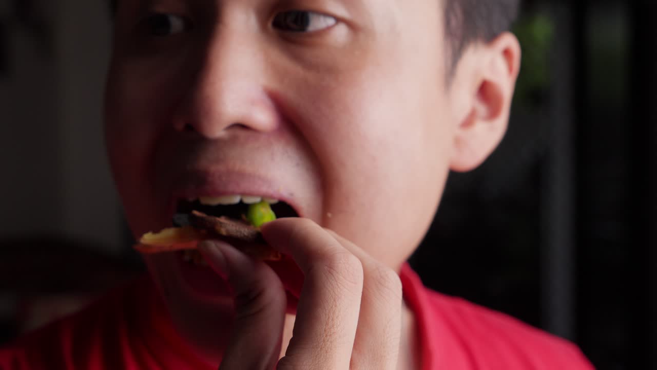 primer plano de un joven vegetariano asiático del sureste comiendo pizza con las manos