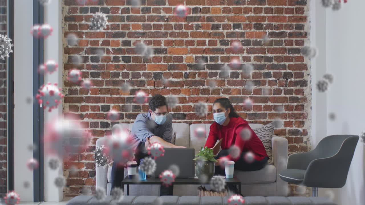 анимация клеток covid-19, плавающих над мужчиной и женщиной в масках, использующих ноутбук в офисе