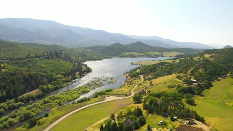 Vista-Aérea-De-La-Arveja-Floreciente-En-Las-Colinas-Con-El-Lago-Emigrante-En-El-Fondo