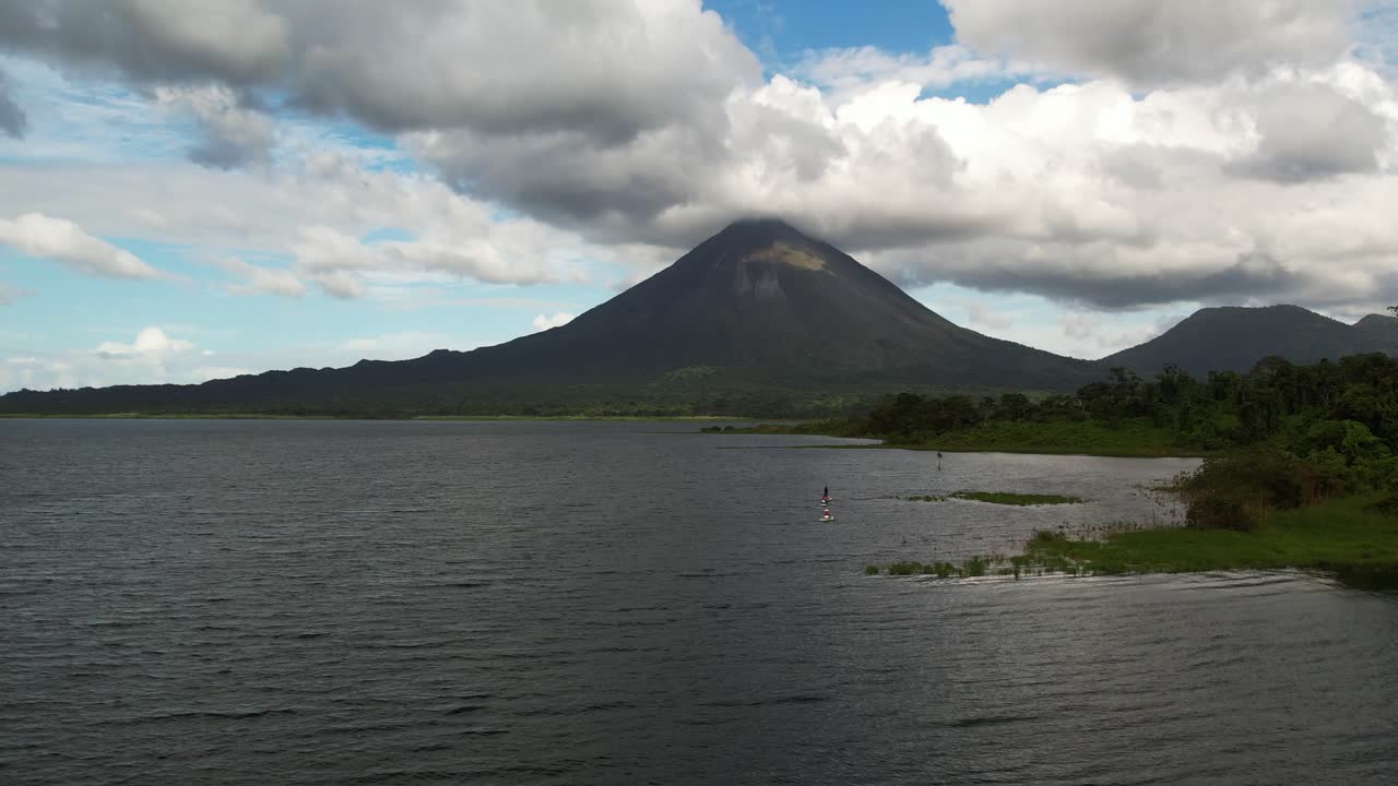 Enorme pico de vulcão tropical e lago entre nuvens