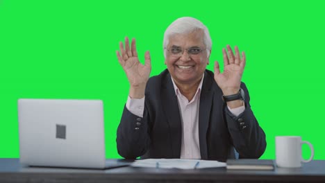 happy senior indian businessman saying hello and waving green screen