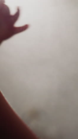 little boy shakes off talcum powder from hands at bright light in room. toddler finishes professional boxing training in modern gym closeup slow motion