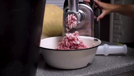 mincing fresh pork meat with electric machine in domestic kitchen