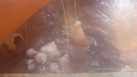 personas cocinando ofrendas en agua de manantial caliente sagrada natural durante el día desde diferentes ángulos