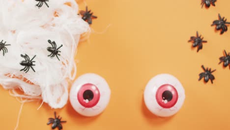 Close-up-view-of-scary-eyes-and-spider-toys-against-orange-background