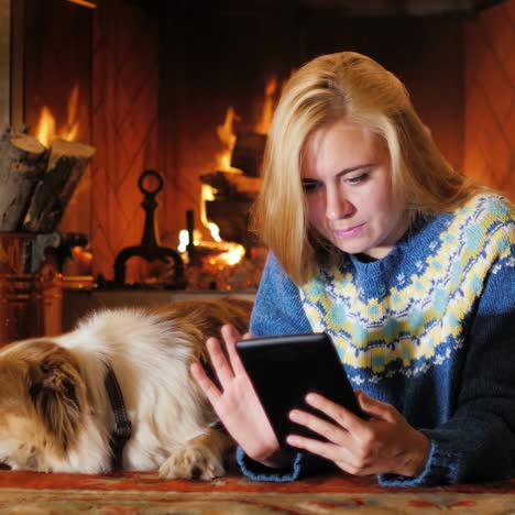 caucasian young woman lying by the fireplace use the tablet