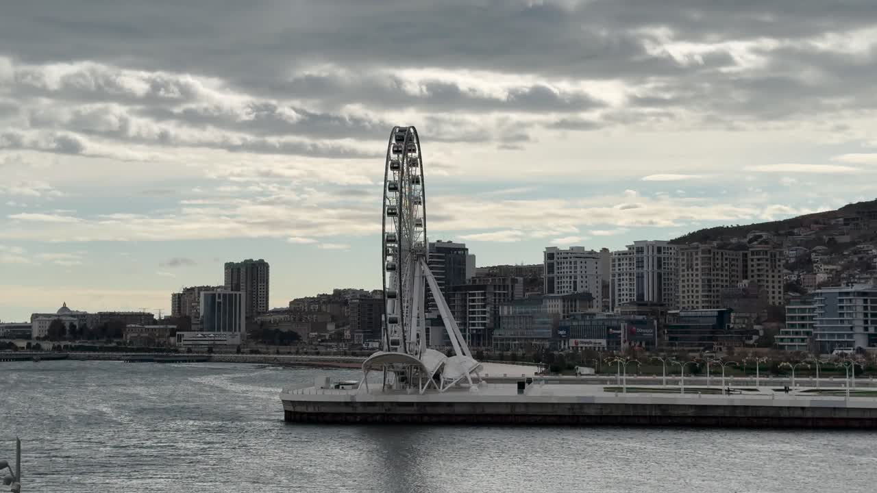 Large Ferris wheel on Baku Boulevard facing Caspian Sea, framed by modern skyline. Baku, Azerbaijan