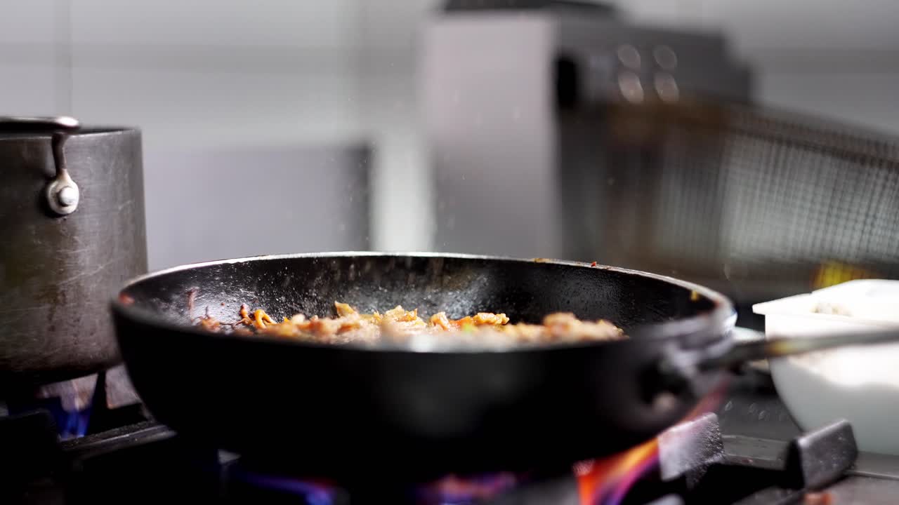 Close up and cinematic view of a chef salting a beef stew in a pan in slow motion in a restaurant's cuisine.